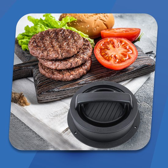 Een gestapelde stapel hamburgerpasteitjes, twee halve tomaten en sla met een zwarte hamburgerpers ernaast.
