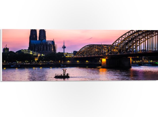 PVC Schuimplaat - Uitzicht op de Dom en Brug van Keulen tijdens de Avondzon in Duitsland - 60x20 cm Foto op PVC Schuimplaat (Met Ophangsysteem)