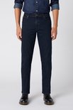 Model draagt een donkerblauwe Wrangler regular fit jeans en een spijkerhemd met zwarte schoenen.