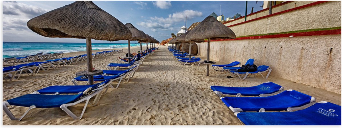 Poster Glanzend – Blauwe Ligbedden op Strand met Rieten Parasols - 120x40 cm Foto op Poste