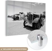 MuchoWow® Glasschilderij 60x40 cm - Schilderij acrylglas - Twee vintage auto's in de woestijn - zwart wit - Foto op glas - Schilderijen