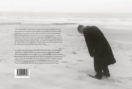 Man in lange zwarte jas loopt op een strand, met de zee op de achtergrond. De tekst vermeldt het project 'The river curls around the town'.