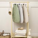 Drie Meyco babyslaapzakken in groen, grijs en beige aan een rek.