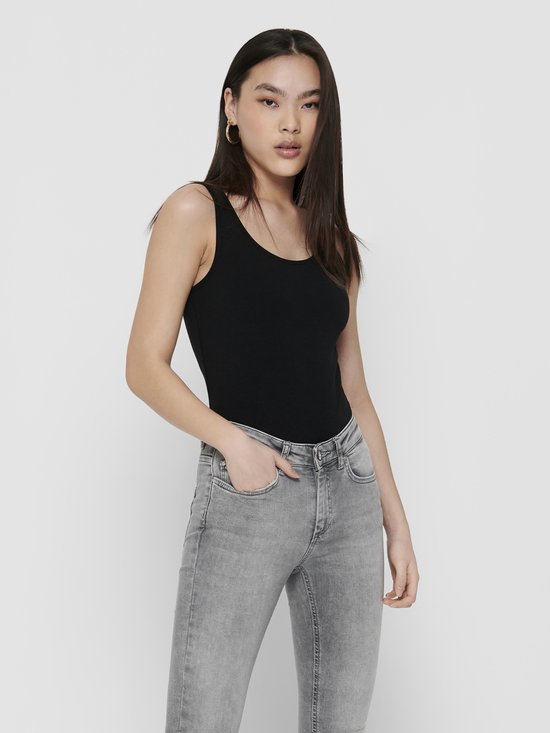 Model met zwarte tanktop en grijze jeans, kijkend naar de camera.