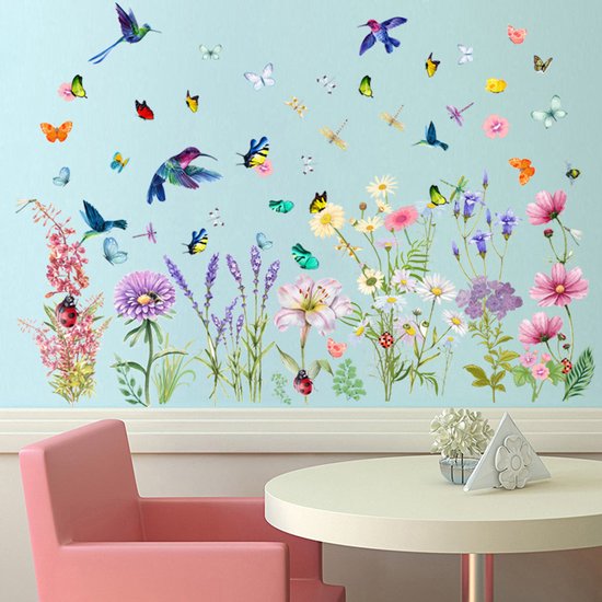 Décoration murale avec des fleurs, des papillons et des colibris sur un mur bleu clair, avec une chaise rose et une table blanche.