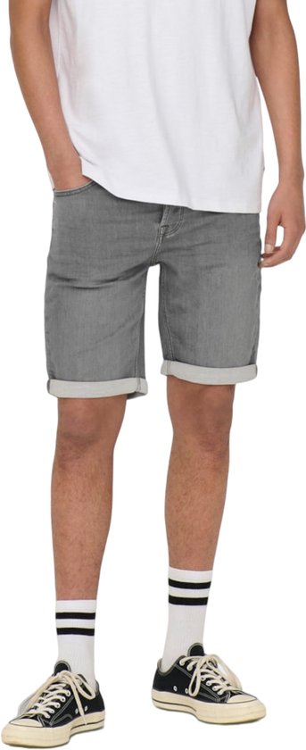 Voorkant van een man in een grijze denim short met omgeslagen broekspijpen en gestreepte sokken.
