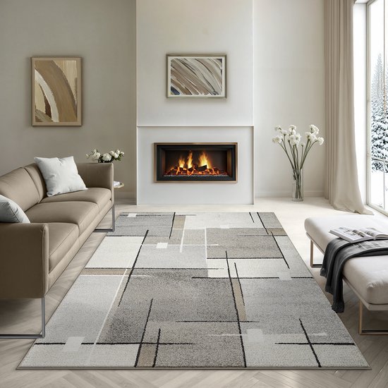 Un salon meublé de façon moderne avec un canapé beige, une cheminée et un tapis au motif abstrait gris, beige et crème.