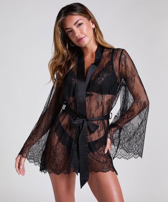 Model in zwarte kanten kimono met wijde mouwen en satijnen ceintuur.