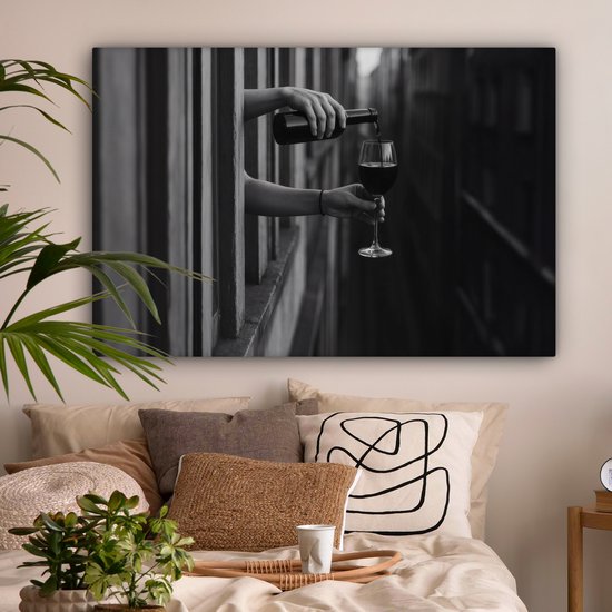 Zwart-wit canvas van handen die wijn schenken, opgehangen boven een gezellig bed in een slaapkamer.