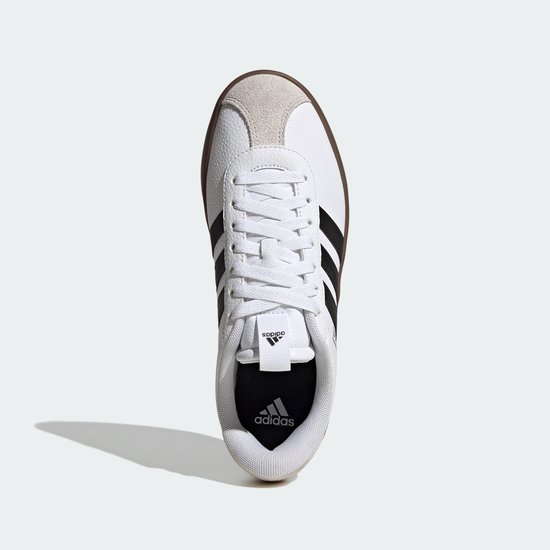 Witte Adidas sneaker met zwarte strepen en een bruine zool, gezien vanaf de bovenkant.