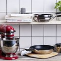 Keukenopstelling met rode mixer, twee pannen en kookboeken.