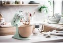Pistachekleurige KitchenAid keukenmachine met een beige kom met beslag en een metalen kom.