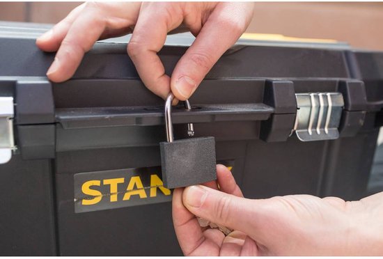 Een hand sluit een hangslot op een zwarte Stanley gereedschapskist.