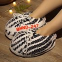 Close-up van voeten in zachte zwart-witte sneaker-pantoffels met rode BNND-247 tekst.