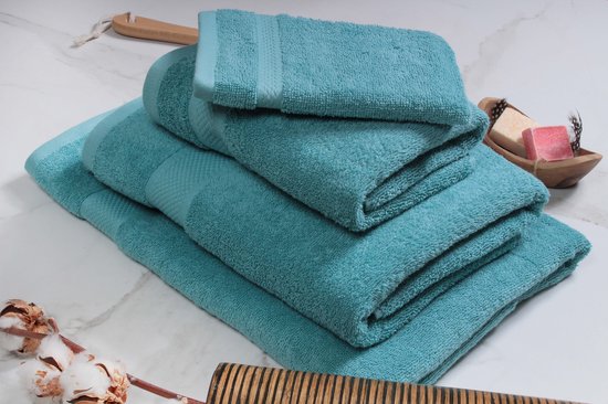 Une pile de serviettes bleu clair avec un motif détaillé sur les bords, avec une plus petite serviette sur le dessus.