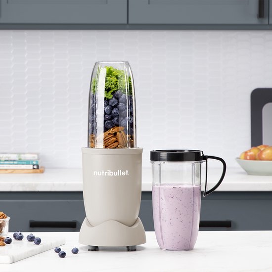 Linnen beige Nutribullet met beker vol bosbessen en pecannoten en een smoothie in een beker met handvat.