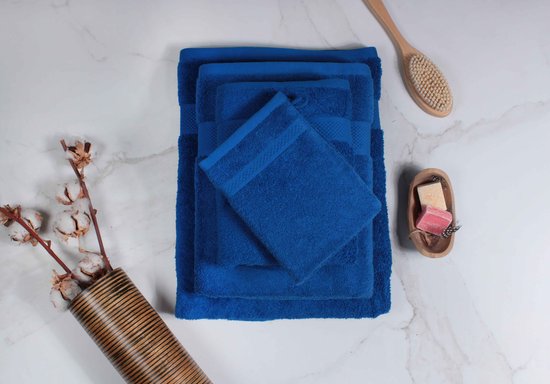 Trois serviettes bleues de différentes tailles, un gant de toilette, une brosse de lavage en bois et une coupelle en bois avec du savon.