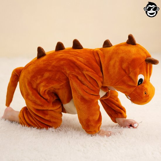 Kind in bruine dinosaurus onesie kruipt over de grond.