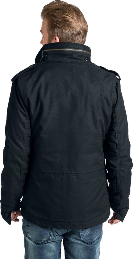 Zwarte herenjas met hoge kraag, epauletten en klepzakken. Gedragen met spijkerbroek.