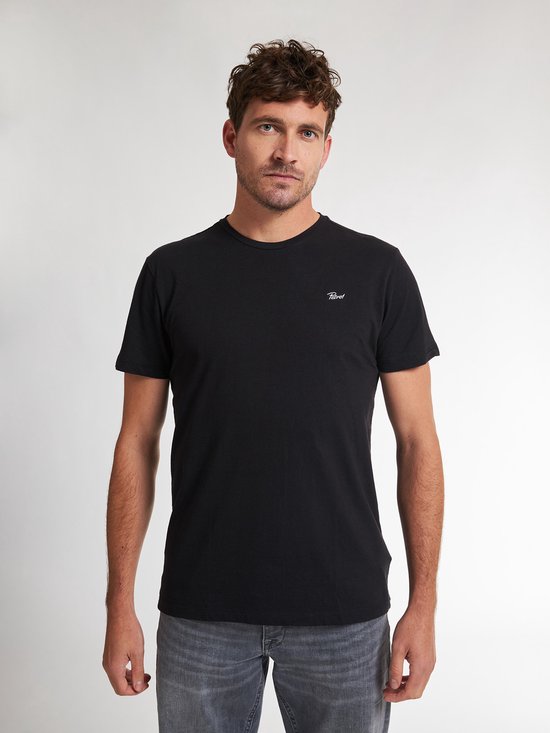 Man met zwarte T-shirt met korte mouwen en een kleine witte 'Petrol' tekst opdruk op de linkerborst, gezien vanaf de voorkant.