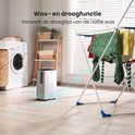 Witte Auronic luchtontvochtiger op de vloer naast een wasrek met natte was in een wasruimte. Een wasmachine staat op de achtergrond.