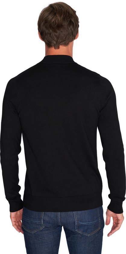 Zicht op de achterkant van een man in een zwarte coltrui en jeans.