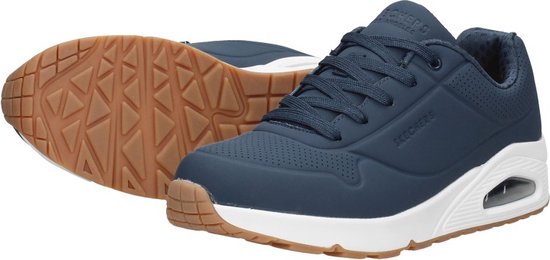 Blauwe Skechers sneakers met witte zolen en bruine neuzen, één schoen ligt op zijn kant.