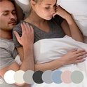 Een stel ligt samen in bed, met kleur samples van verschillende hoeslakens.