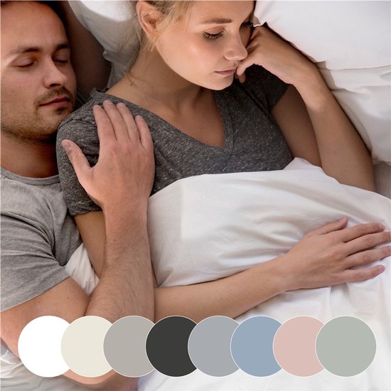 Een stel ligt samen in bed, met kleur samples van verschillende hoeslakens.