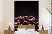 Behang - Fotobehang Stapel donkerbruine koffiebonen tegen zwarte achtergrond - Breedte 180 cm x hoogte 280 cm