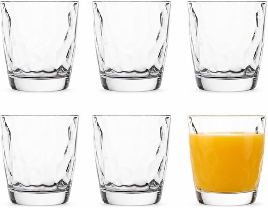 Six verres au motif ondulé unique. Un verre rempli de jus d'orange.