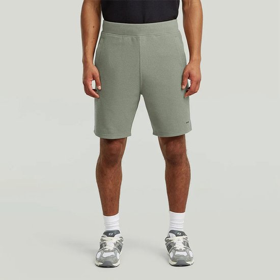 Man in lichtgroene, gestructureerde jersey shorts met zakken.