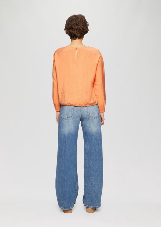 Model draagt oranje s.Oliver blouse met blauwe jeans, achterkant.