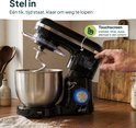 Vingerafdruk op touchscreen van zwarte keukenmixer met metalen kom en deeg.