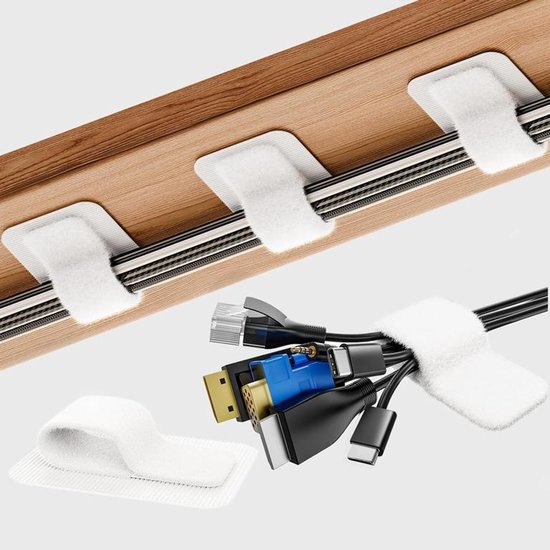 Attaches-câbles blancs en velcro fixés à un bureau en bois, avec une liasse de câbles noirs et bleus.