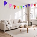 Guirlande festive avec des fanions triangulaires multicolores au-dessus d'un canapé beige dans un salon.