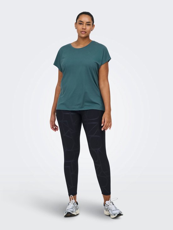 Model in een petrolkleurig sportshirt met korte mouwen en een zwarte legging met grafische print, staand.