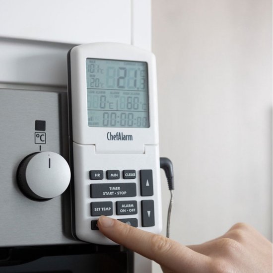 Vinger drukt op de knop 'SET TEMP' van een witte ChefAlarm oventhermometer, op de zijkant van een oven.