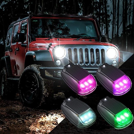 Vier zonne-aangedreven lampen naast een rode Jeep: paarse, witte en groene verlichting.