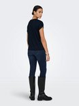 Donkerblauw T-shirt met opgerolde korte mouwen, gedragen door een model met spijkerbroek en laarzen.