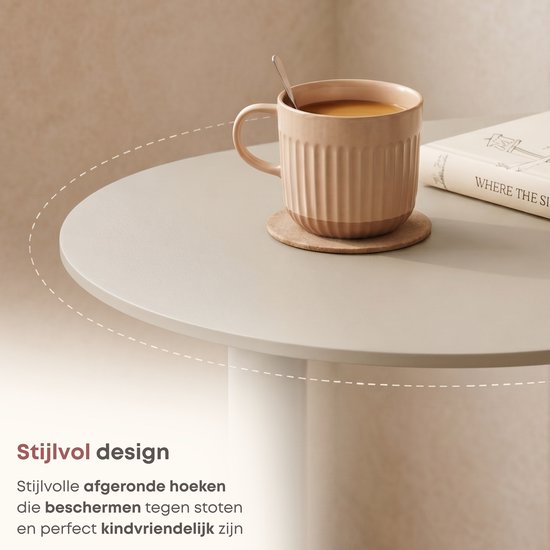Close-up van het ronde, taupe tafelblad van een bijzettafel met een gegroefde mok koffie.