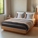 Gedaan opgemaakt bed met een dekbed met bruine, beige, grijze en witte strepen, en een ruitpatroon aan de onderkant.