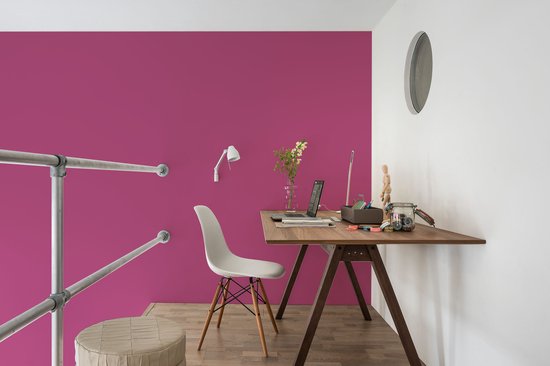 Een bureau met fuchsia muur, witte stoel en houten vloer.