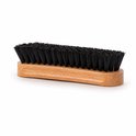 Brosse à manche en bois et poils de textile noirs, sur fond blanc.