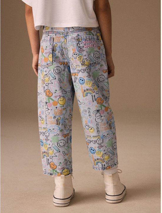 Achterkant van lichtblauwe, wijde jeans met all-over print van Smiley World-figuren en het 'Smiley World'-logo op de achterzak.
