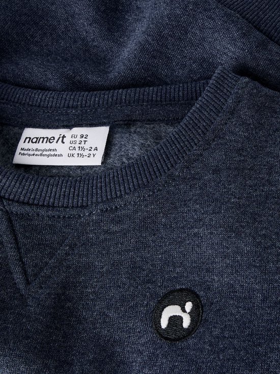 Label van een donkerblauwe sweater met de tekst 'name it' en maatinformatie.