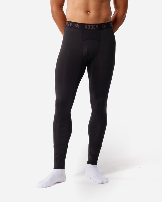 Homme les mains derrière le dos, portant un legging long thermique noir.