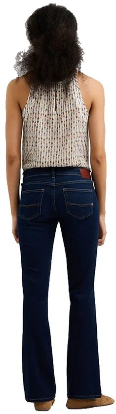 Achterkant van donkerblauwe bootcut jeans met lage taille op model met een bedrukte mouwloze top.