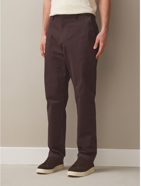Man in een beige poloshirt en een bruine chino.