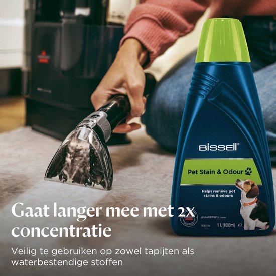 Gebruiker met BISSELL Pet Stain & Odour fles en opzetstuk voor reiniger op een tapijt.